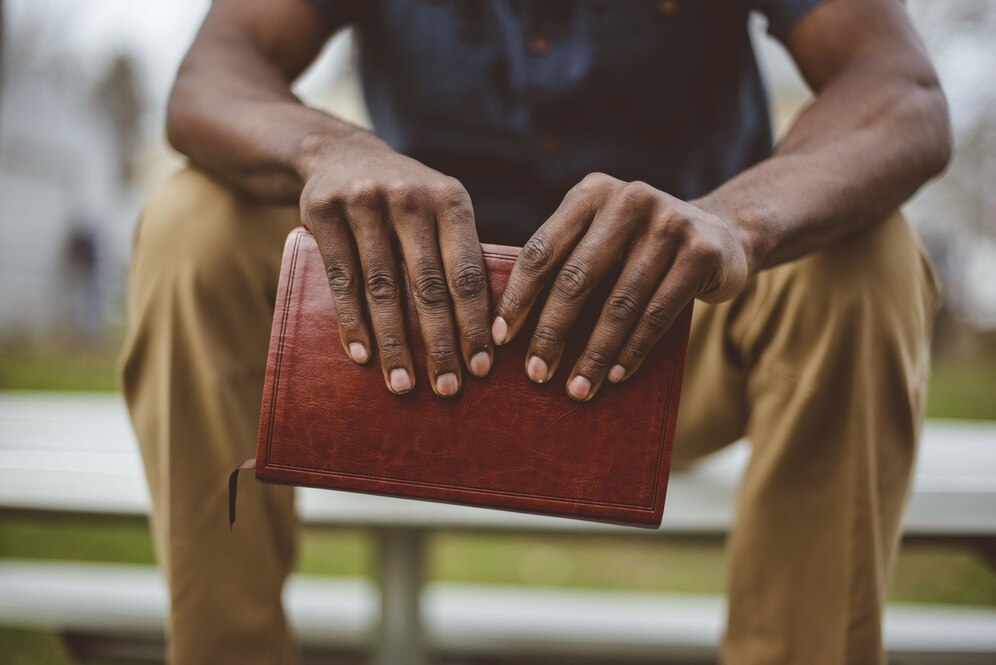 closeup-shot-male-sitting-park-while-holding-bible_181624-8367